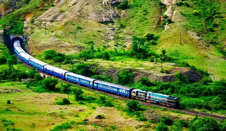 Tren Ferrocarriles Indios saliendo de túnel colinas verdes — experiencia auténtica de viaje India principiantes TTI Tours
